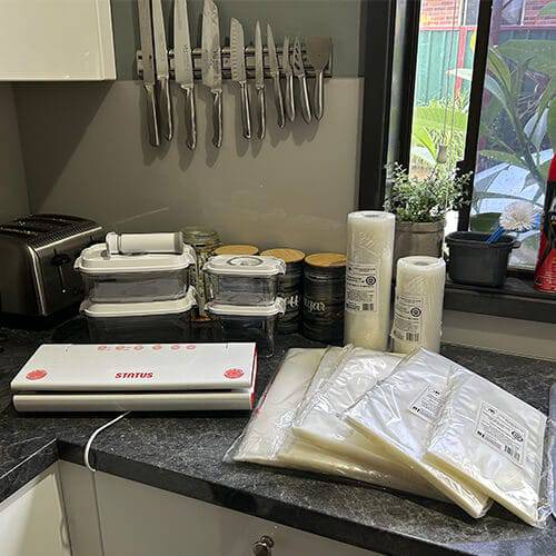 vacuum sealer, vacuum sealer bags, vacuum sealer rolls and vacuum canisters on a kitchen bench